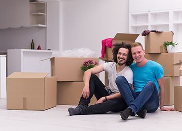 A couple with their arms around each other in front of moving boxes