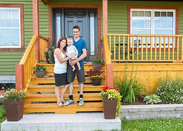 A couple with a baby in front of a colorful house