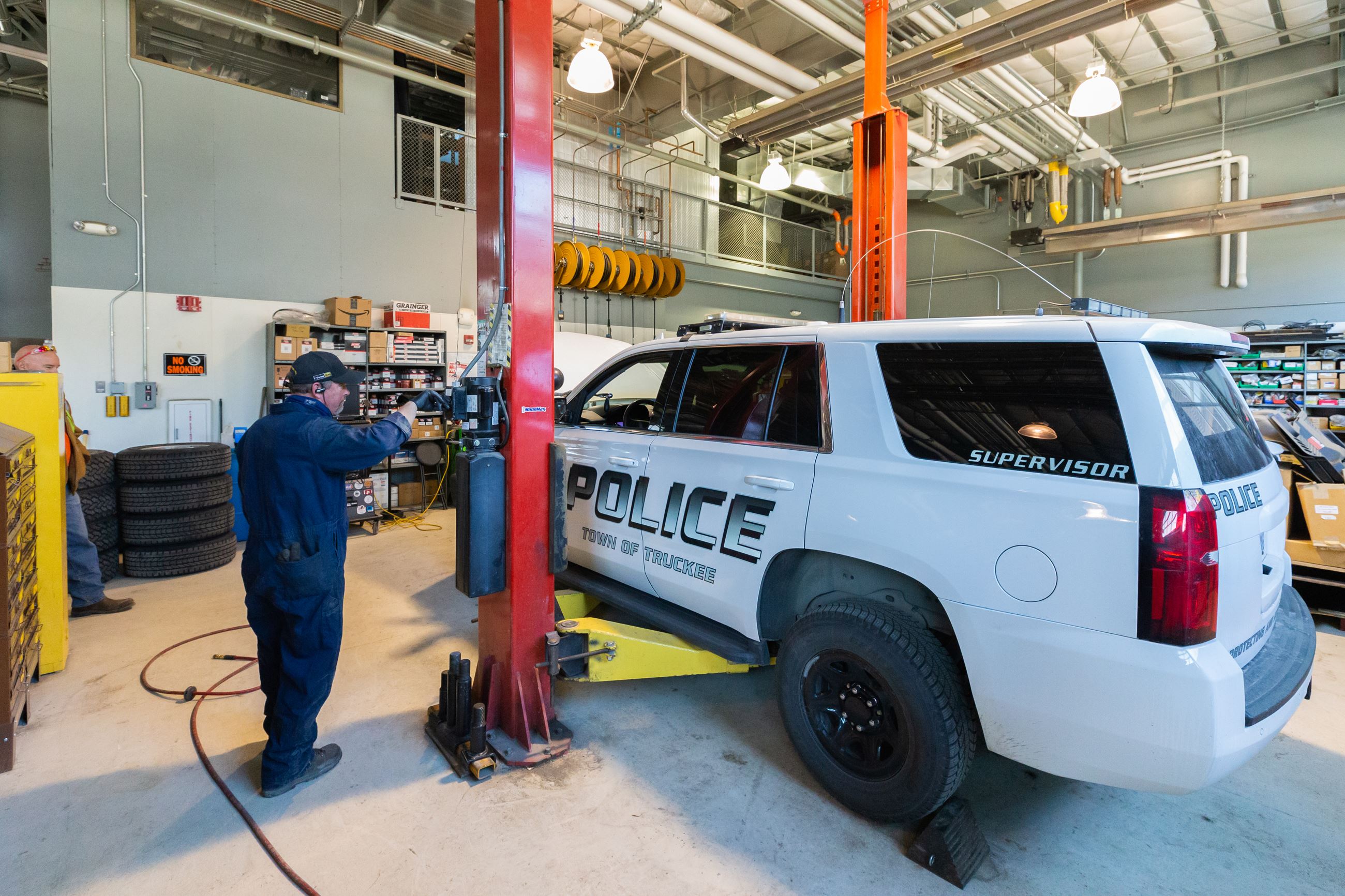 Mechanic lifting up a police car with a leaver in a garage. 