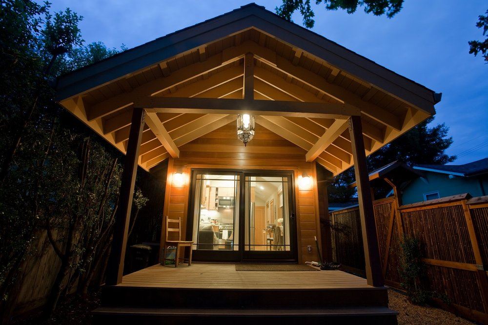 A wooden ADU at night with a big covered deck