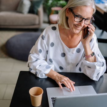 Women on her phone and laptop smiling. 