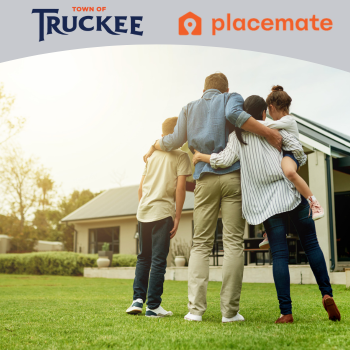 Family hugging together looking at a house with their back to the camera. 