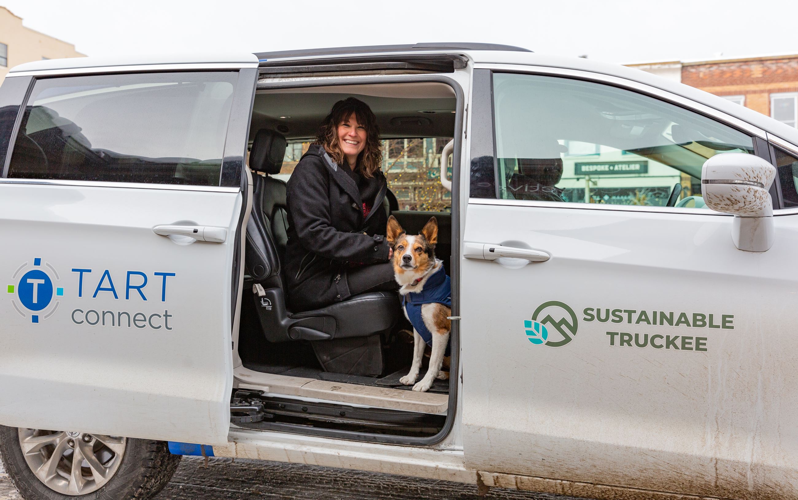Women sitting in TART van with door open and dog sitting at her feet looking out. 